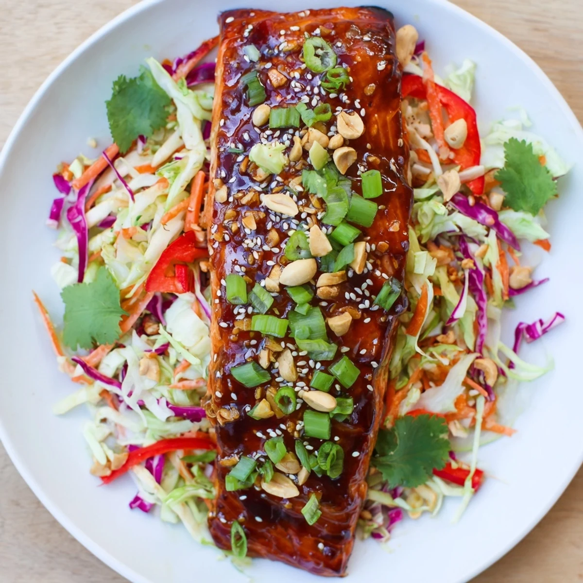 Golden teriyaki salmon sits atop colorful Asian slaw, perfect for a refreshing Teriyaki Salmon meal.