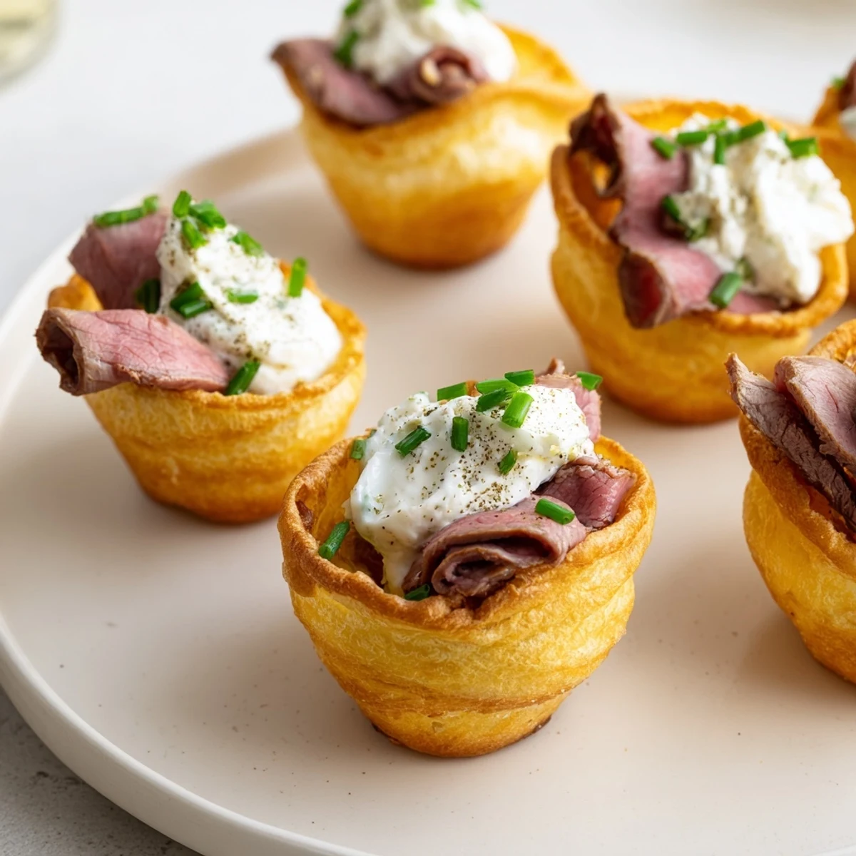 Warm, crispy Express Holiday Yorkshire Pudding Bites brimming with savory roast beef and garnished green chives.