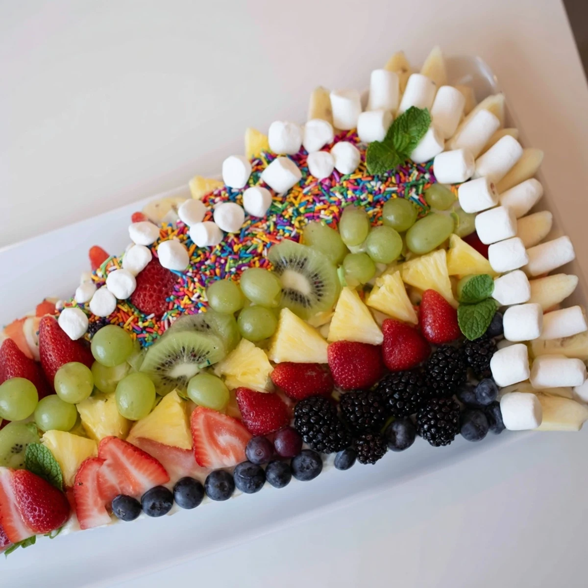 Vibrant Happy Birthday Cake Slice Fruit Board featuring juicy strawberries, kiwi, and sweet blueberries.