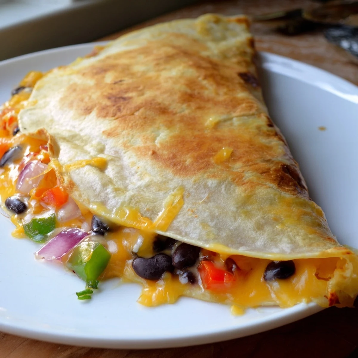 Golden, cheesy Black Bean Quesadilla, with melted cheese and fresh vegetables, ready to serve.