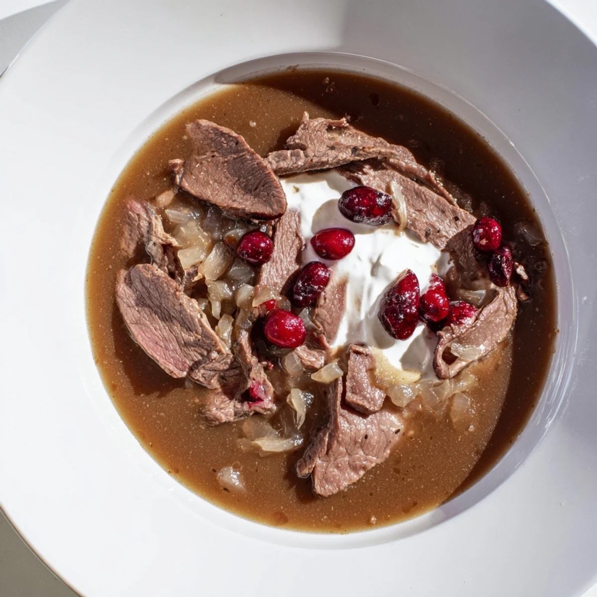Tender Finnish Reindeer Stew, with vibrant lingonberries and creamy sour cream, ready to serve hot.