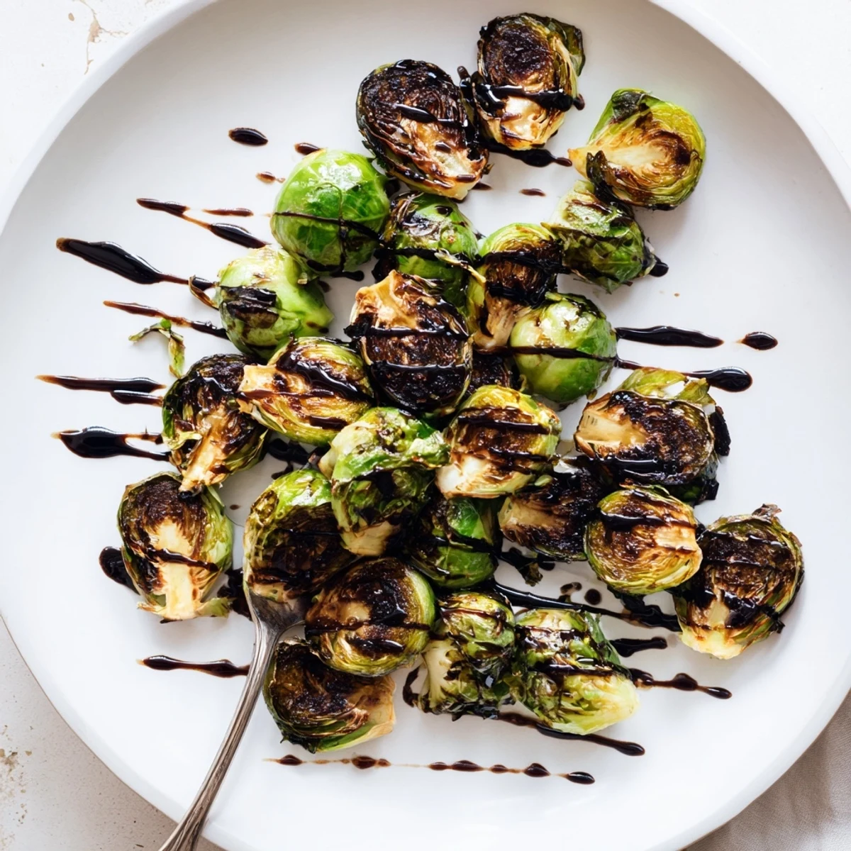 A close-up of Roasted Brussels sprouts with balsamic glaze, showing tender centers and crispy, golden-brown leaves.
