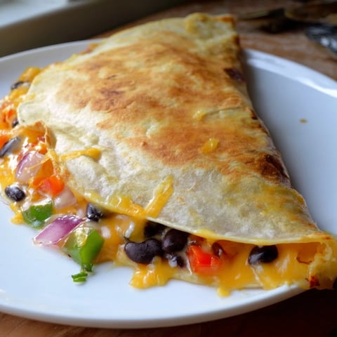 Golden, cheesy Black Bean Quesadilla, with melted cheese and fresh vegetables, ready to serve.