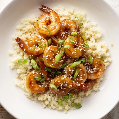 Vibrant ginger garlic shrimp bowls served with fluffy cauliflower rice, drizzled with savory soy sauce.