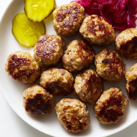 Golden-brown Danish frikadeller, perfectly pan-fried and ready to be served with traditional, tangy pickles.