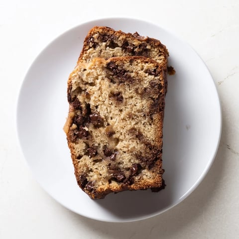 A freshly baked loaf of moist banana bread with chocolate chips, still warm from the oven.