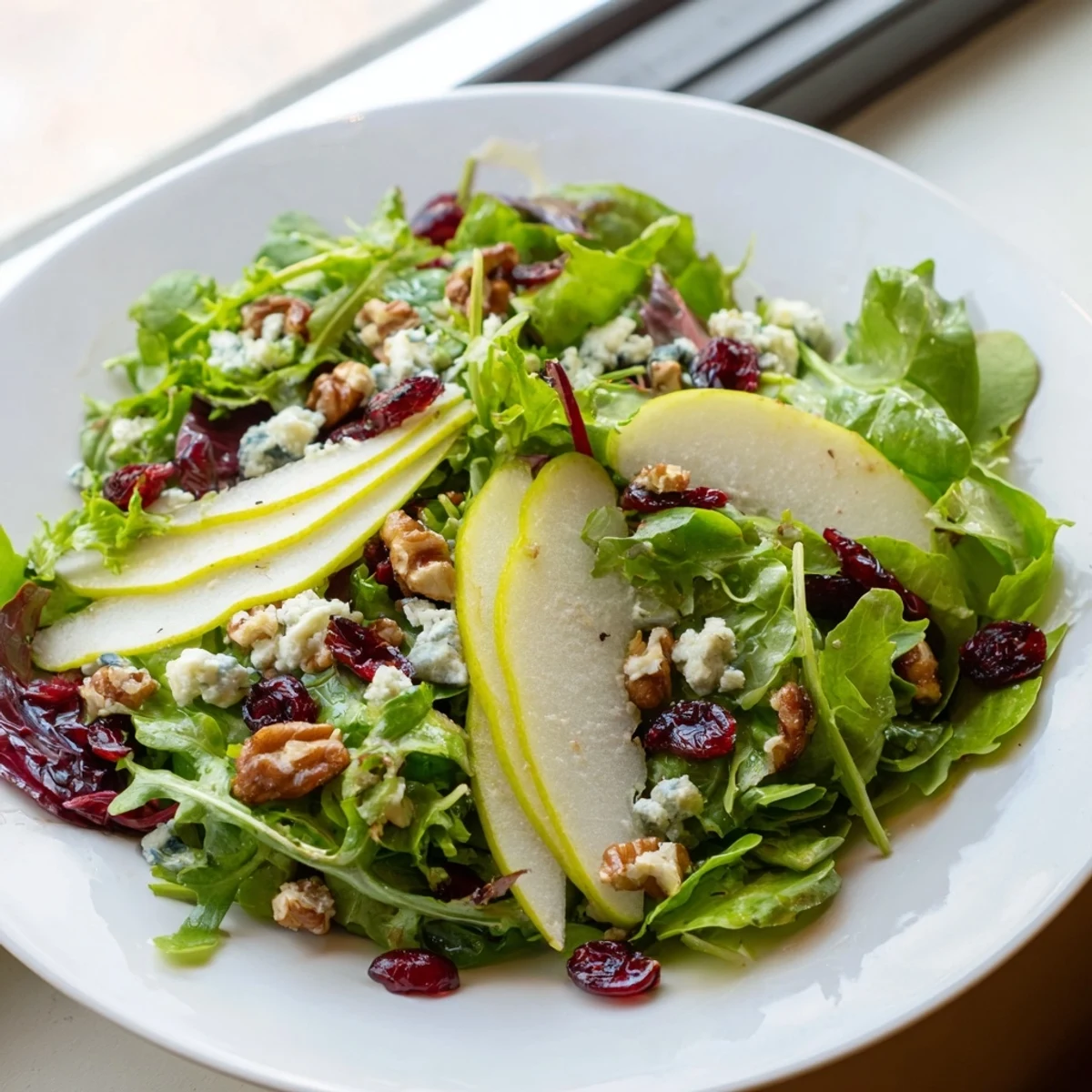 Fresh, crisp salad greens topped with juicy pear slices, crumbled Gorgonzola, and toasted walnuts, drizzled with honey-balsamic vinaigrette.