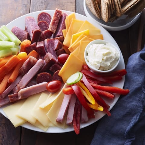 This Budget-Friendly Family Spread offers colorful sliced meats and cheeses arranged on a large platter for a party.