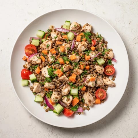 Enjoy a bowl of delicious Chicken and Lentil Recession Salad, with colorful cherry tomatoes and crunchy cucumbers.