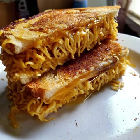 Imagine the savory aroma of melted cheddar in this unique Ramen Grilled Cheese, ready for a bite.