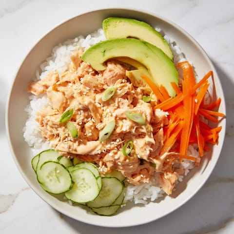 Flaky salmon glistens atop fluffy rice, part of this easy Spicy Canned Salmon Rice Bowl recipe.