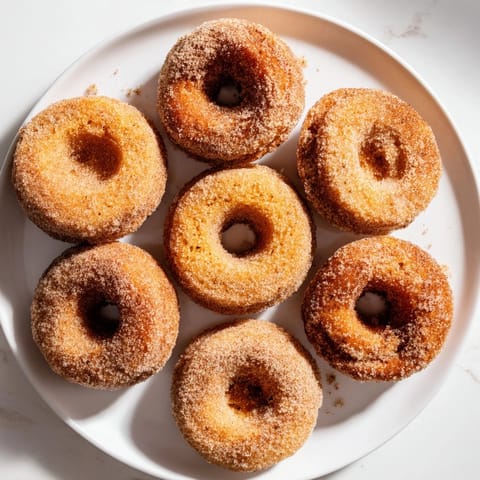 Air Fryer Cinnamon Sugar Donuts cooling on a wire rack, fluffy biscuit dough with visible cinnamon sugar coating, perfect for a quick dessert.