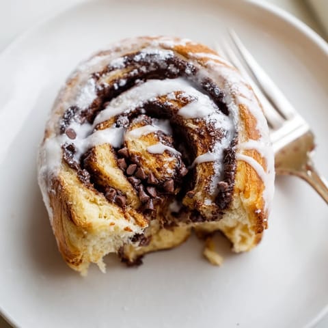 Close-up of freshly baked Nutella Chocolate Chip Rolls, showcasing the golden-brown, soft dough spiraled with melted chocolate-hazelnut spread and melty mini chocolate chips.