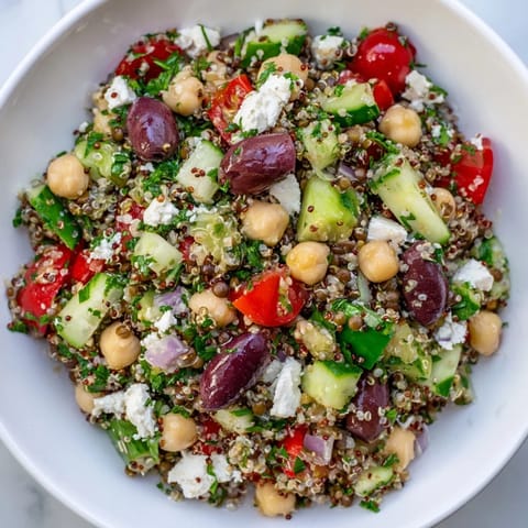 Close-up of a colorful Greek Power Salad with Kalamata olives and cherry tomatoes, drizzled with a zesty Greek vinaigrette.