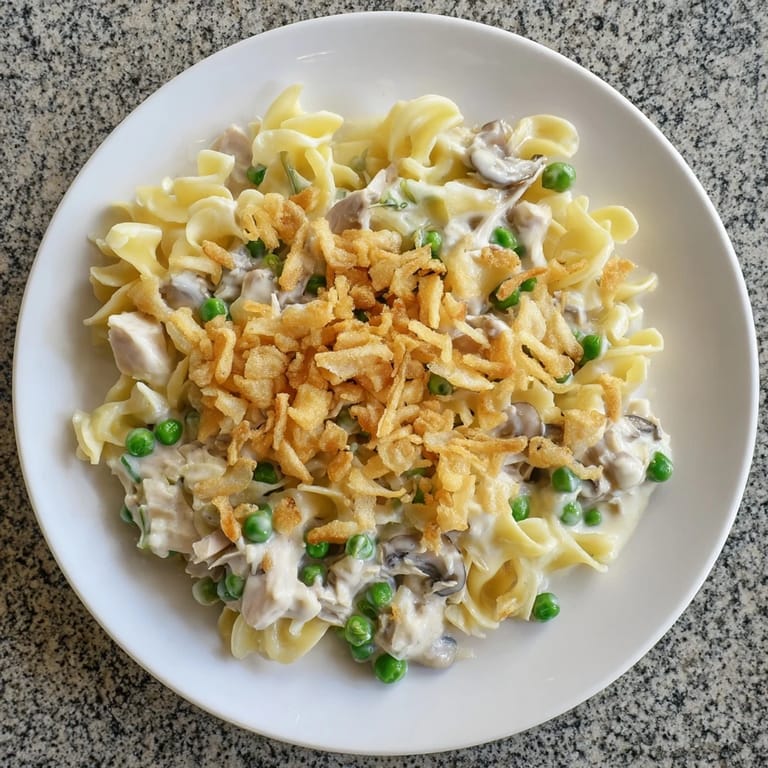 A close-up of a bubbling tuna noodle casserole, showcasing creamy sauce and golden crust.