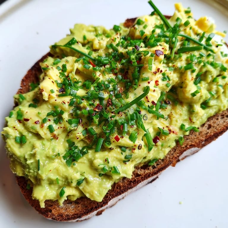 Freshly made Avocado Egg Smash with vibrant herbs, ready to be spread on warm, golden toast.