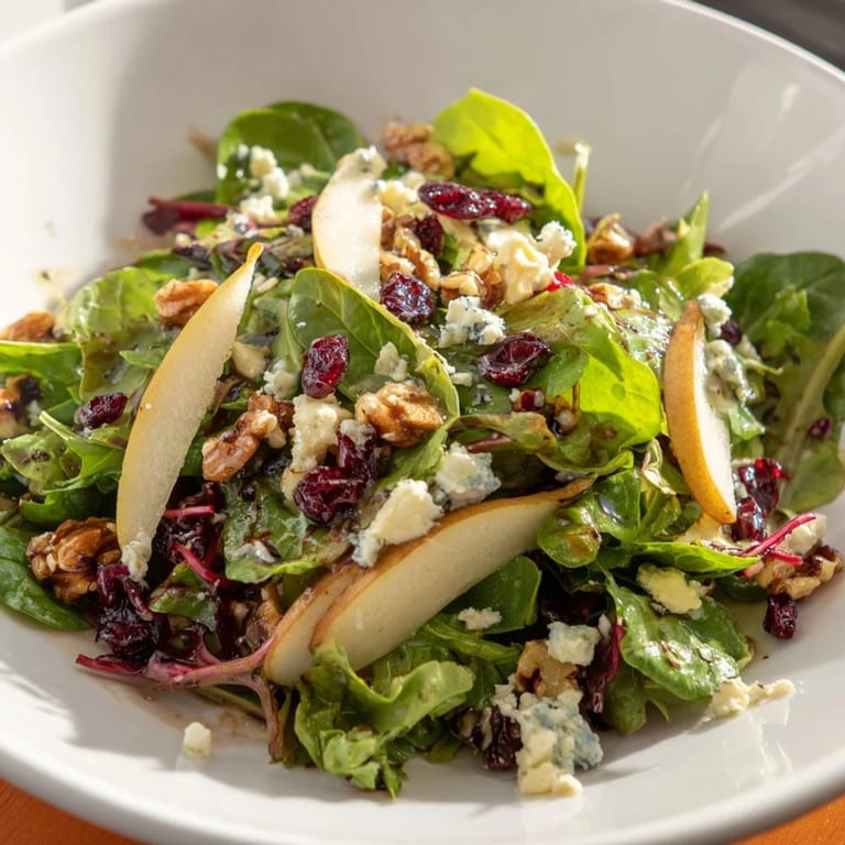 Pear Gorgonzola Salad garnished with crumbled blue cheese and walnuts, served as a refreshing vegetarian starter or light lunch.