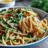 Vibrant lemon butter pasta with peas and Parmesan, a creamy spring dish with bright citrus notes and tender green vegetables.